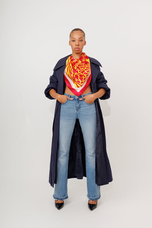 Model in long navy coat wearing bright orange Bana scarf styled as a neckpiece
