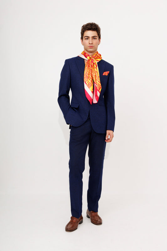 Male model in navy suit wearing orange Bana scarf as necktie
