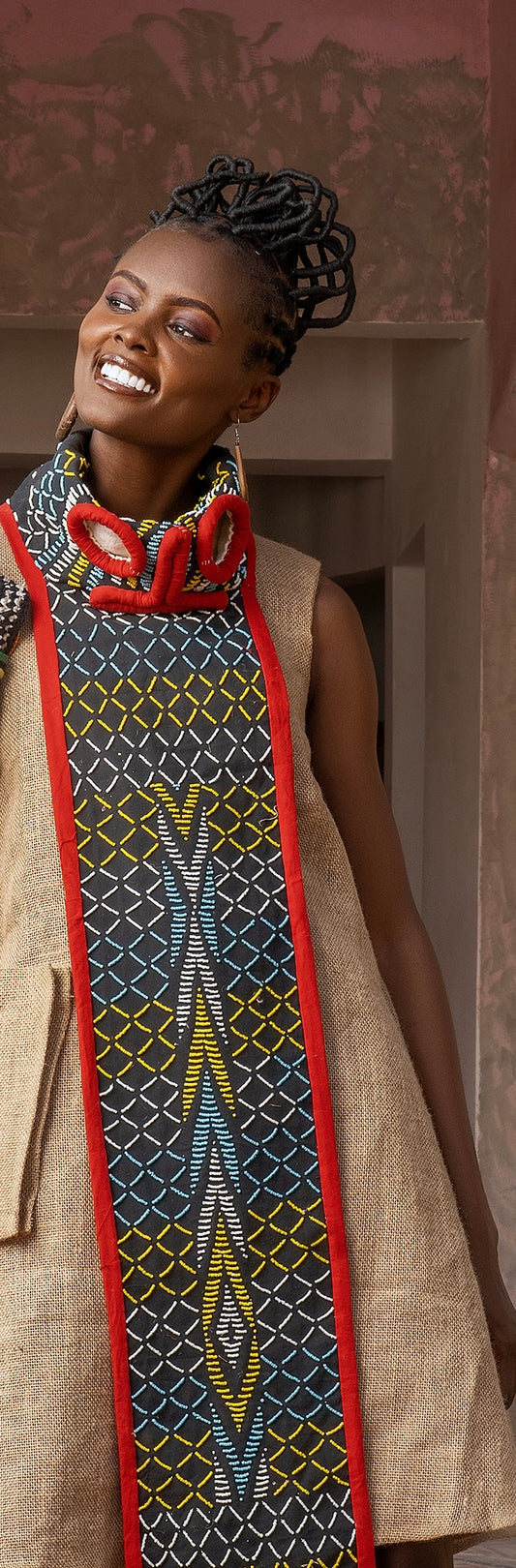 Model smiling in tan dress wearing long Juju mask-inspired beaded necklace
