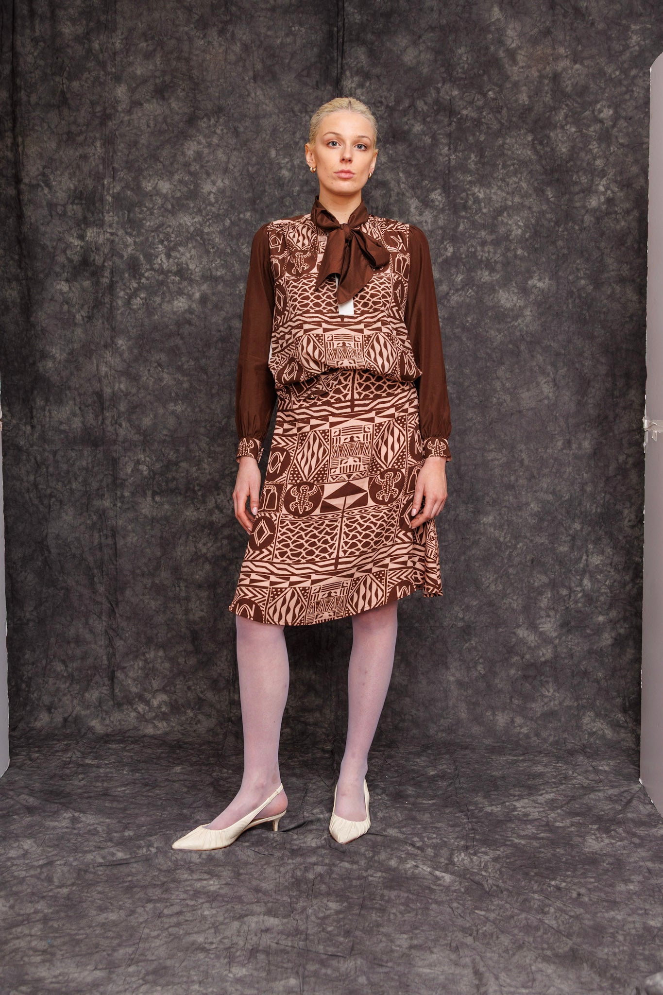 Model wearing Kadji Teo Toned Mocca Blouse styled with skirt, front view